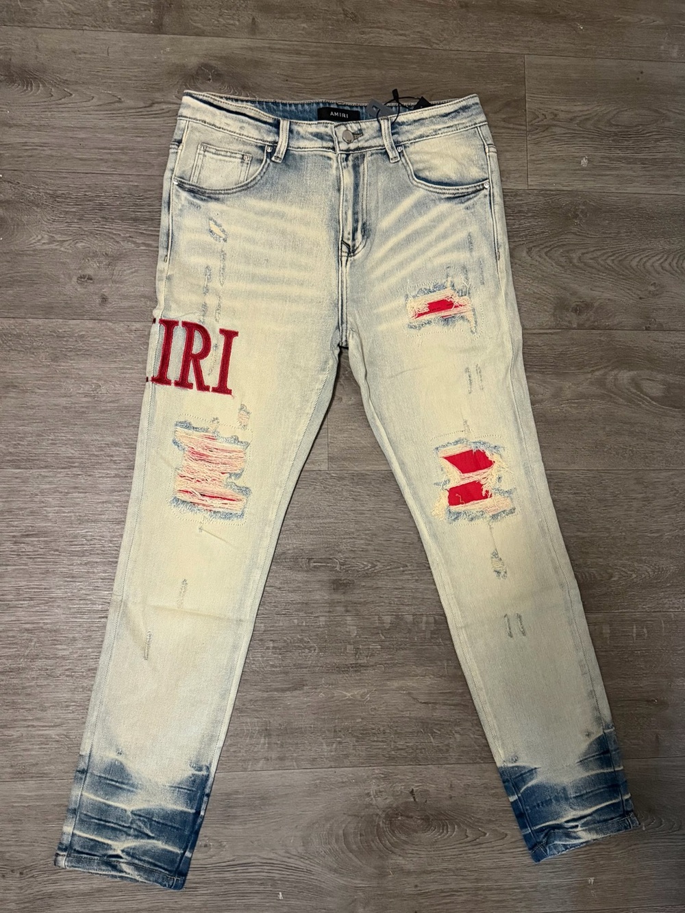 AMIRI Light Wash Distressed Slim Fit Jeans with Red Patch Accents